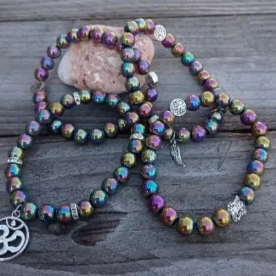 Bracelets en perles irisées multicolores avec breloques argentées, dont un symbole Om, posés sur un fond en bois naturel.