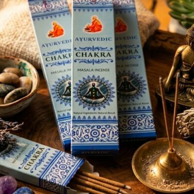 4 boites d'encens ayurvedic chakra posées sur un fond en bois et entouré de 2 encens qui brulent