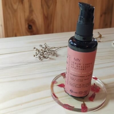 Un serum corps de massage apaisant de la marque MiYé posé sur un sous verre en résine époxy avec des inclusions de fleurs séchées et posé sur une table en bois