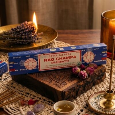 Un paquet d'encens nag champa posé sur un fond en bois et entouré d'un encens qui brule, d'une bougie