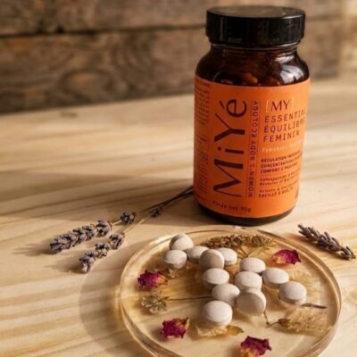 Un flacon de compléments alimentaires pour l'équilibre féminin de la marque MiYé avec un sous verre en résine époxy avec des inclusions de fleurs séchées et dessus des comprimés