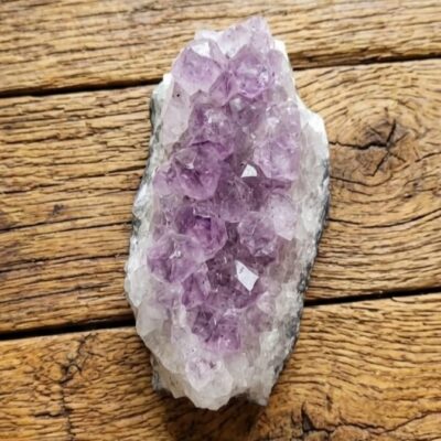une druse d'améthyste violette posée sur un fond en bois